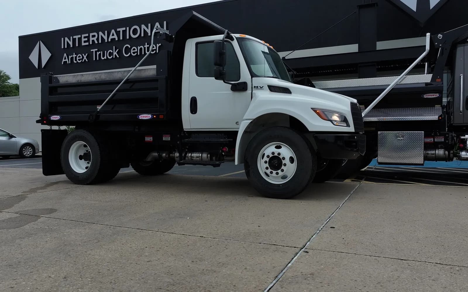 White International MV dump truck in front of the Artex Truck Center building