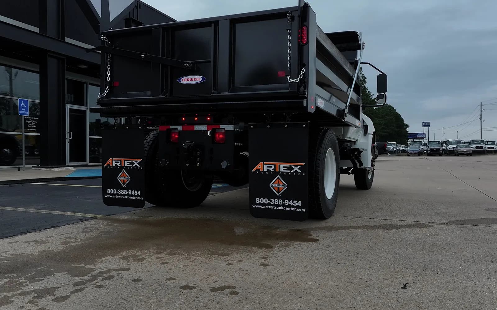 Rear view of a white International MV dump truck showing the Ledwell tailgate badge and Artex International mud flaps