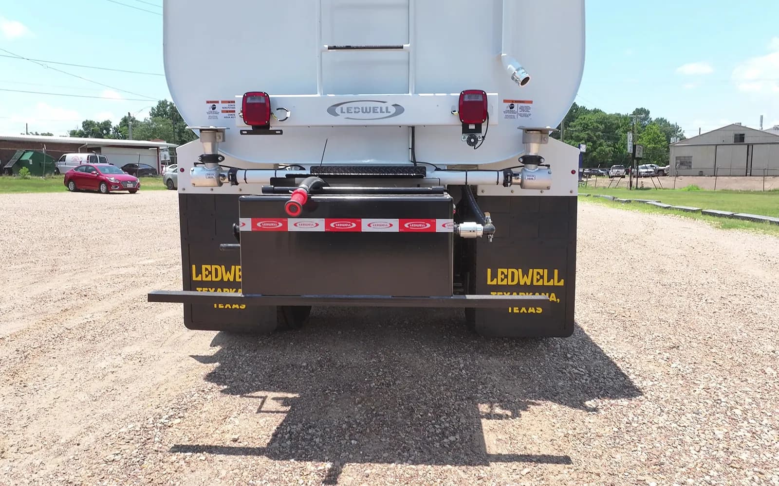 Rear view of a white International HV water truck showing the Ledwell tank, rear spray bar and Ledwell Texarkana mud flaps
