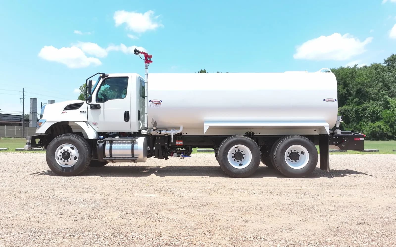 White International HV water truck with a Ledwell tank and water cannon, side view on a gravel lot