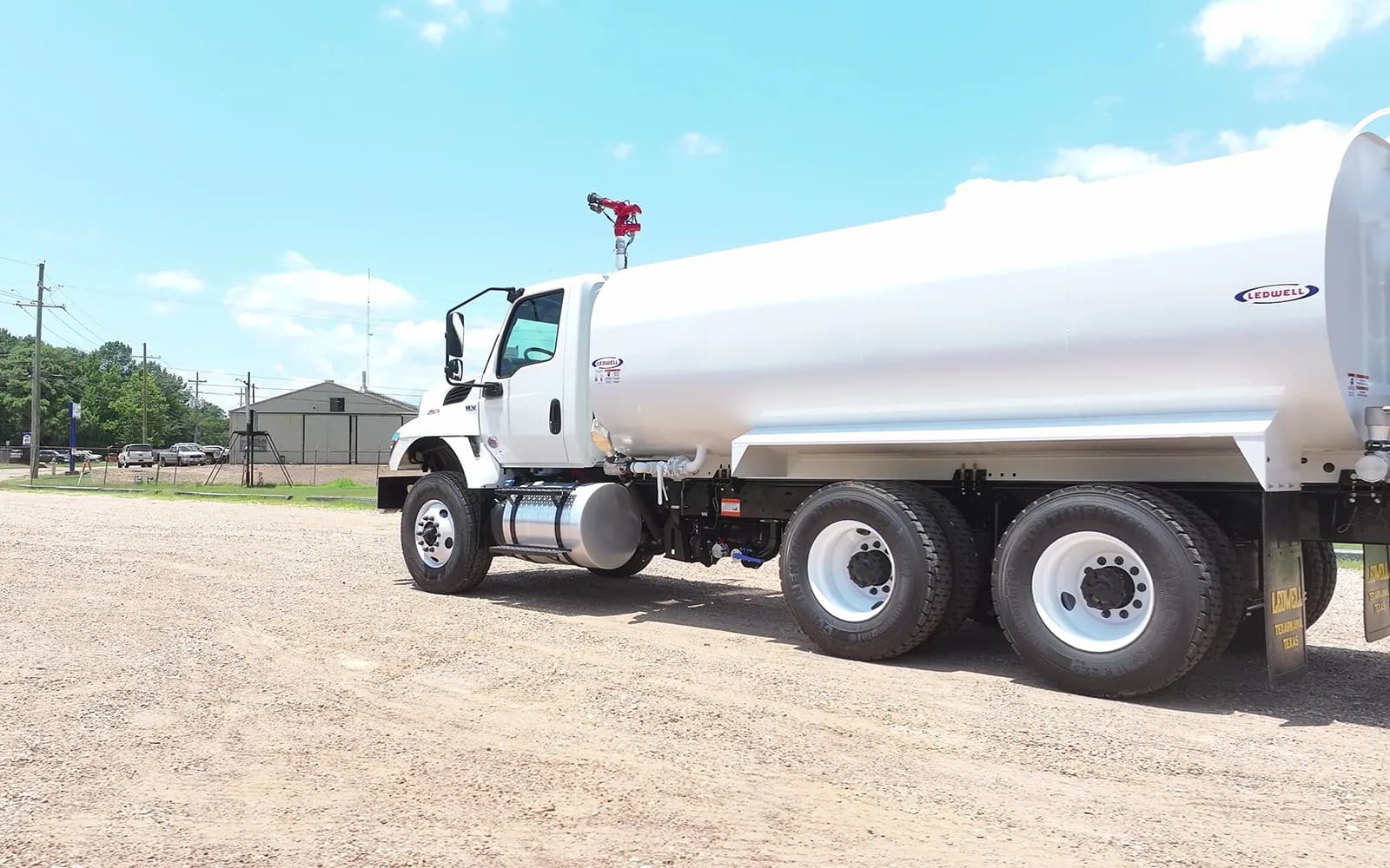 White tandem-axle International HV water truck with a Ledwell water tank and water cannon, side view