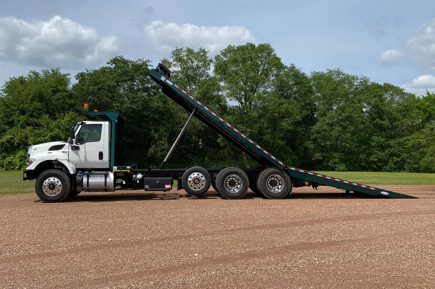 Ledwell HydraTilt tri-axle truck on an International chassis with the deck tilted, side profile