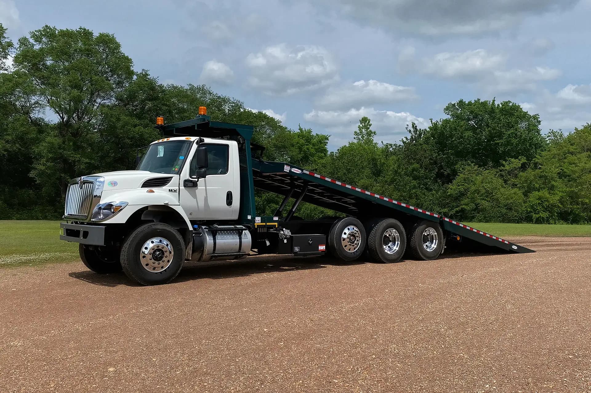 Ledwell HydraTilt tri-axle truck on an International chassis with the deck tilted, front three-quarter view