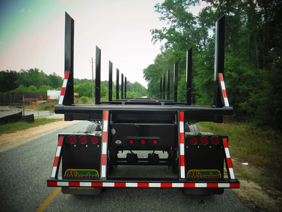 Black McLendon forestry trailer on the road, seen from behind