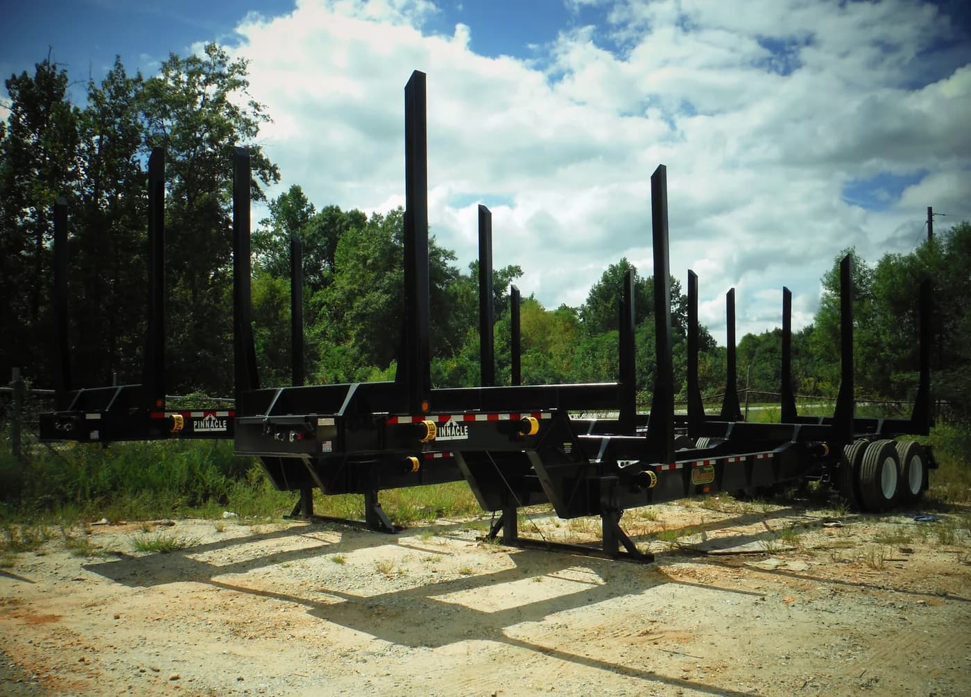 Blue McLendon forestry trailer with empty log bunks under a clear sky