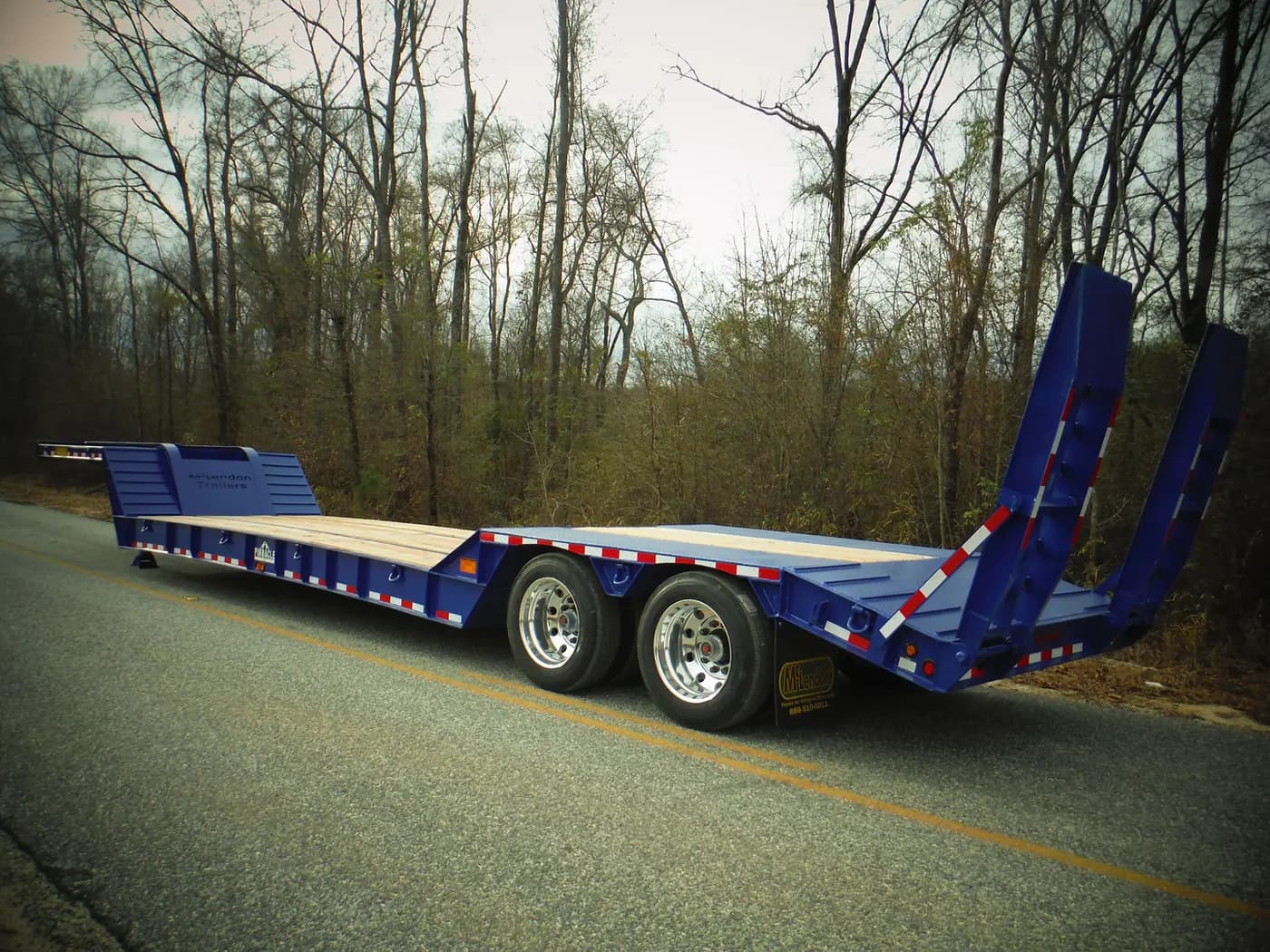 Blue McLendon lowboy trailer with loading ramps lowered