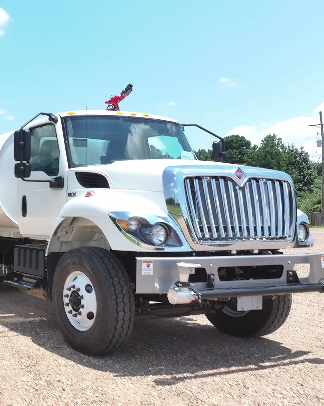 White International HV water truck with a Ledwell water tank, water cannon and Ledwell Texarkana mud flaps, rear three-quarter view on a gravel lot