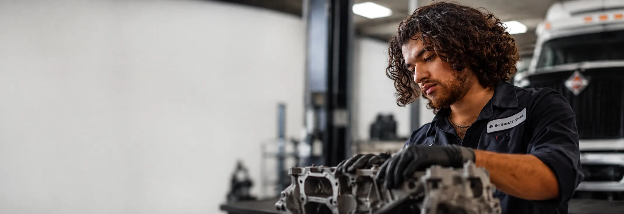 Technician in an International uniform rebuilding an engine in the shop